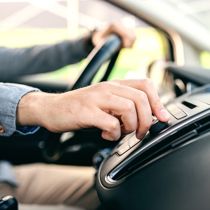 Close up of man changing radio station while driving car.