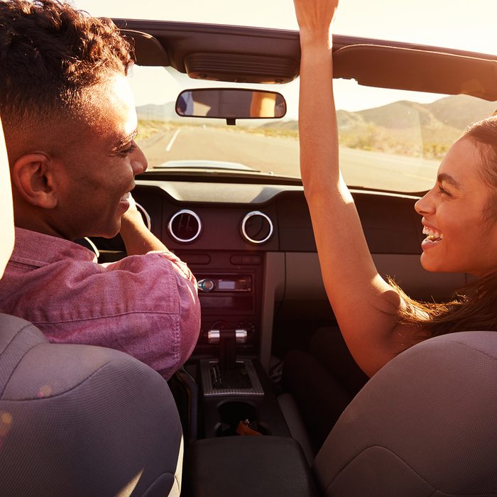 Couple On Road Trip Driving In Convertible Car
