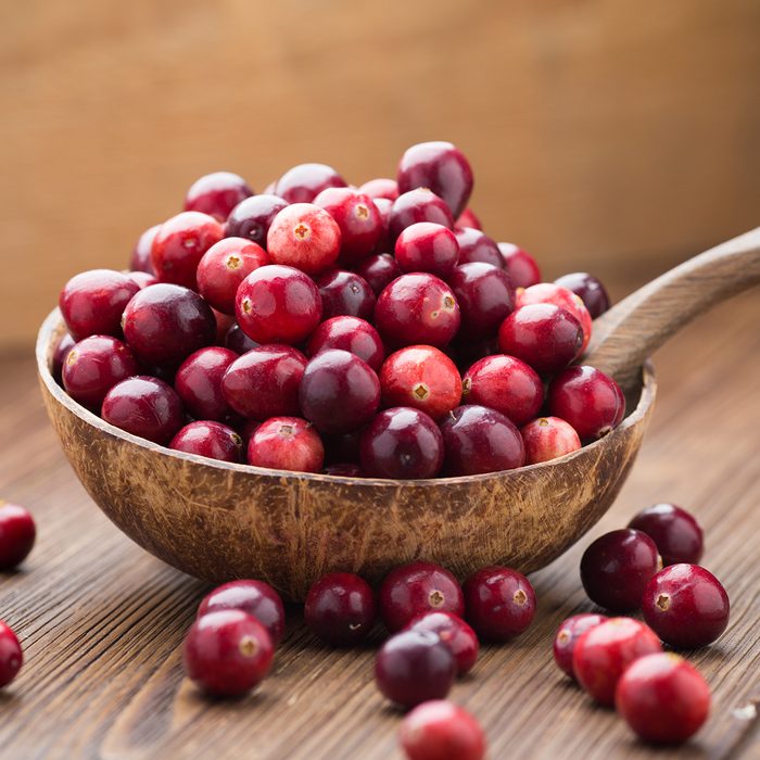 Cranberries in wooden bowl on wooden background.