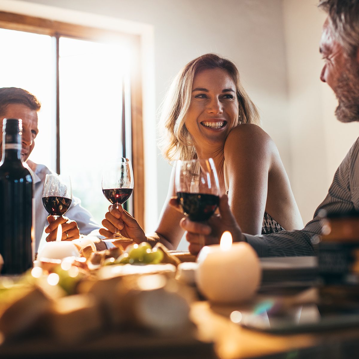 Smiling woman talking with friends sitting at dining tablet at home