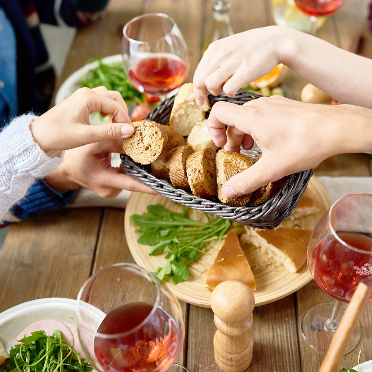 Closeup of unrecognizable people passing bread basket around at festive dinner table