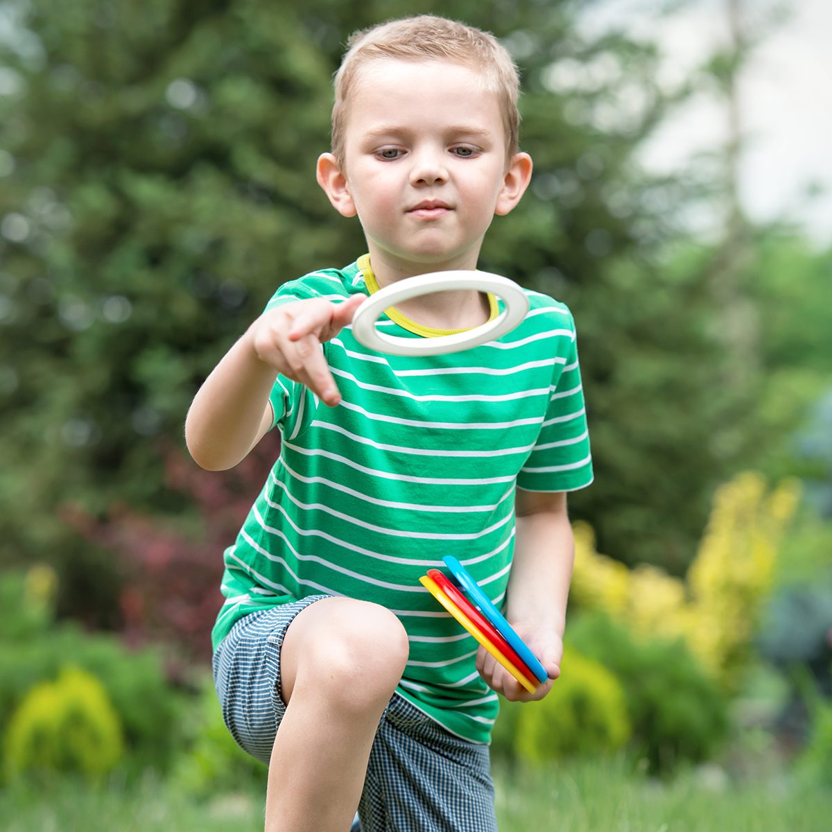 Cute boy playing a game throwing rings outdoors in summer Park