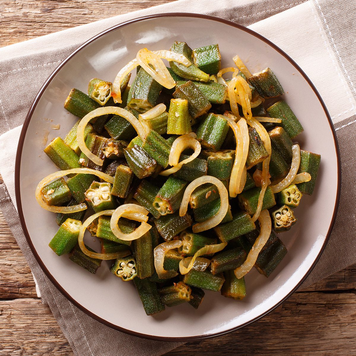 Asian cuisine: green okra fried with onion close-up on a plate on the table.