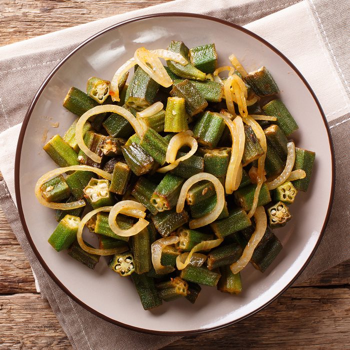 Asian cuisine: green okra fried with onion close-up on a plate on the table.