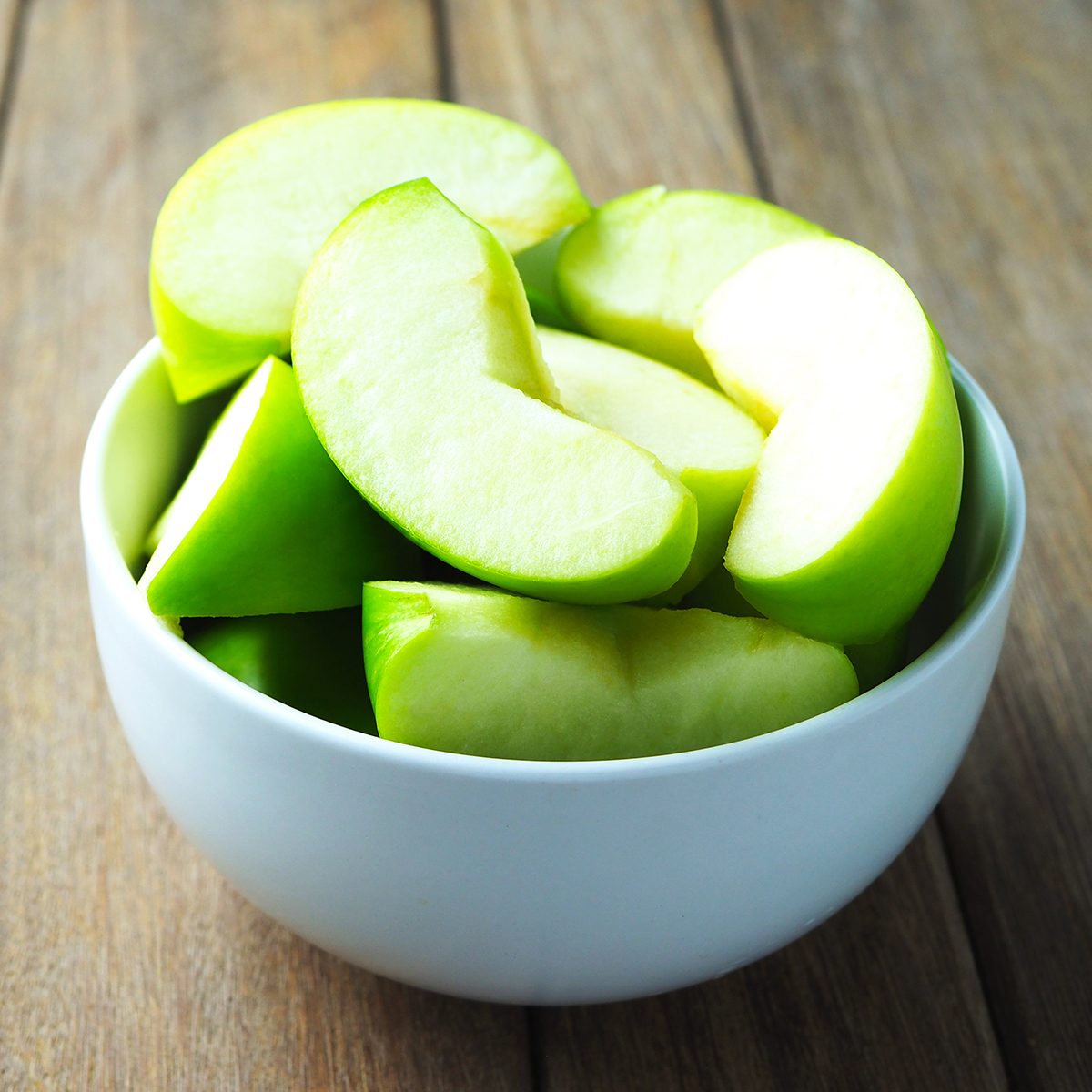 fruits for diabetics Close up of a bowl of apple slices on a wooden table.