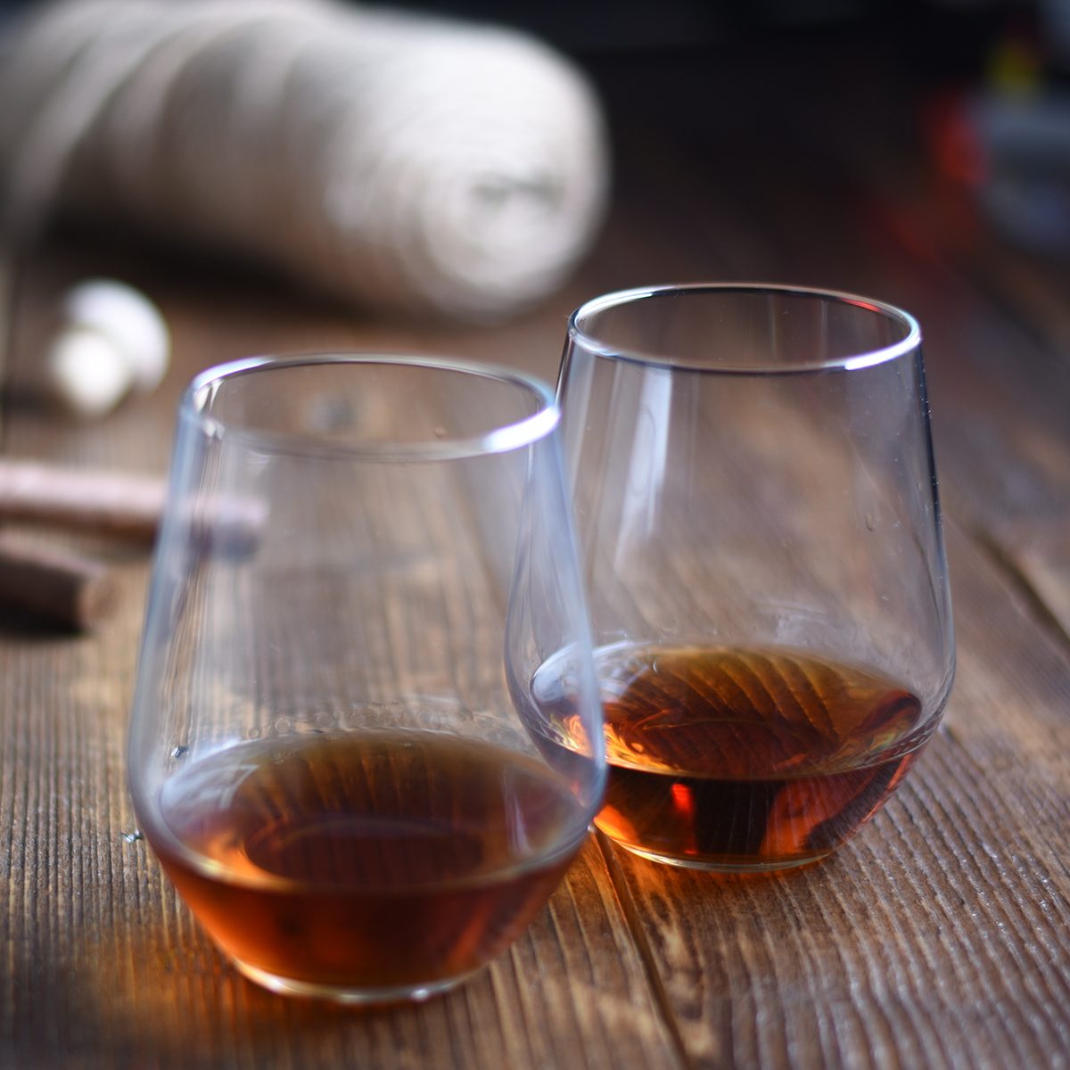 Glass of rum on a rustic wooden table with cigars and bottle.
