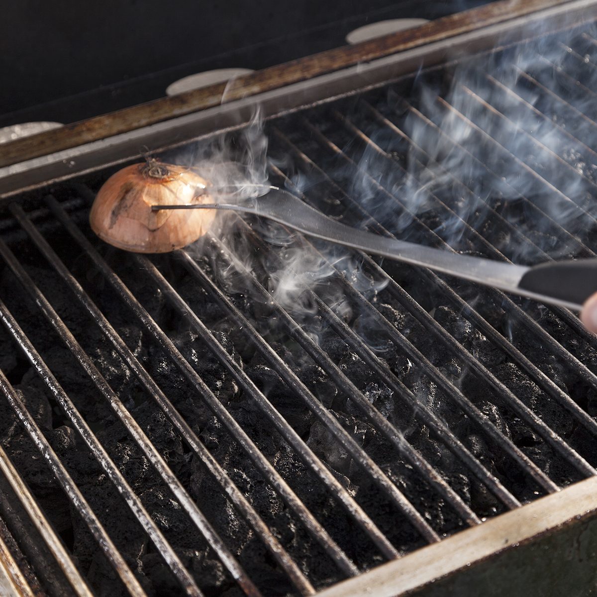 Getting the grill ready for some cooking - rubbing halved onion on the hot grate.