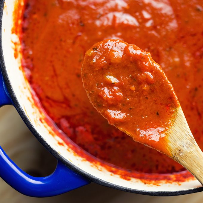 Overhead view of savory marinara, slow cooked all day in an enamel coated cast iron Dutch oven.