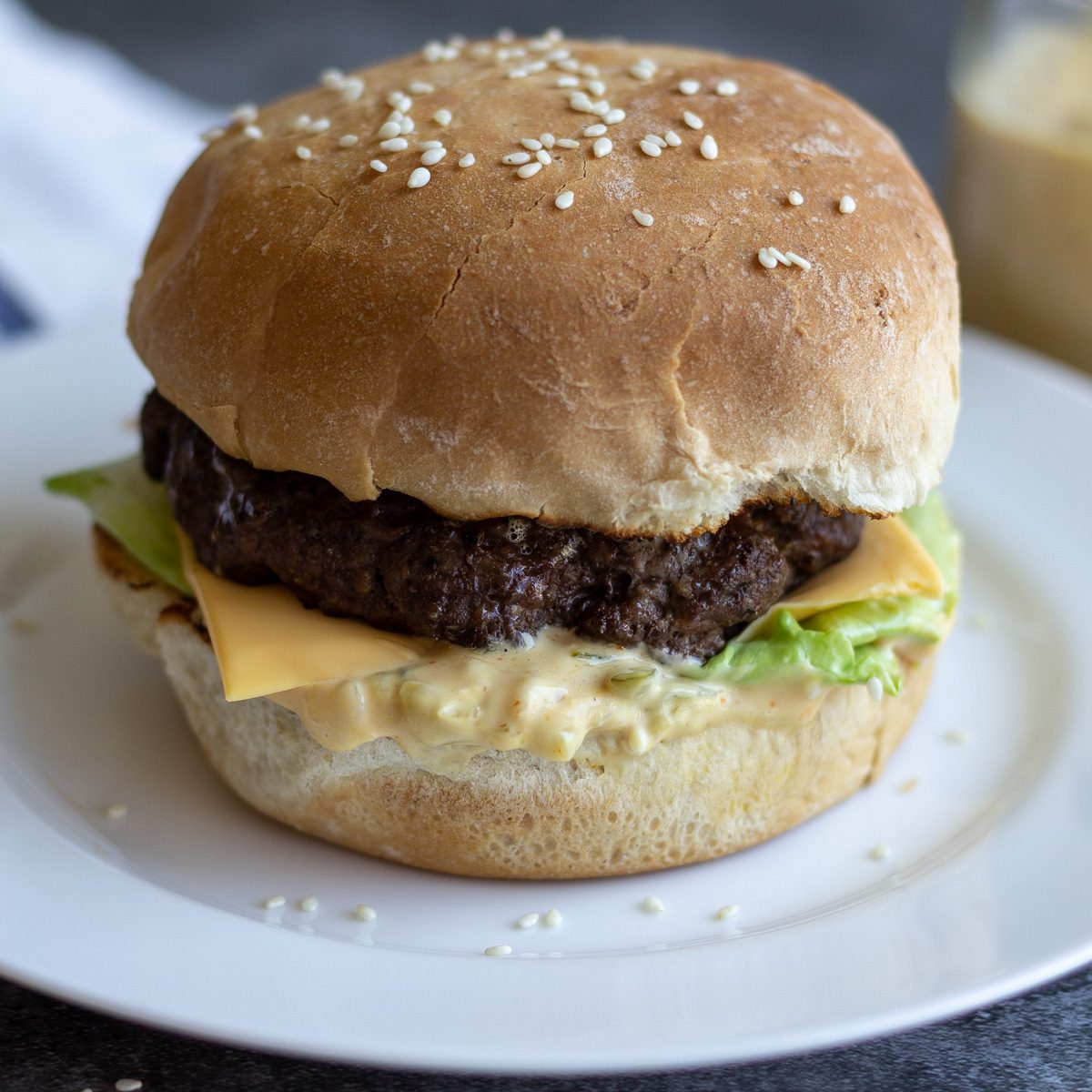Cheeseburger on a roll served on a white plate.