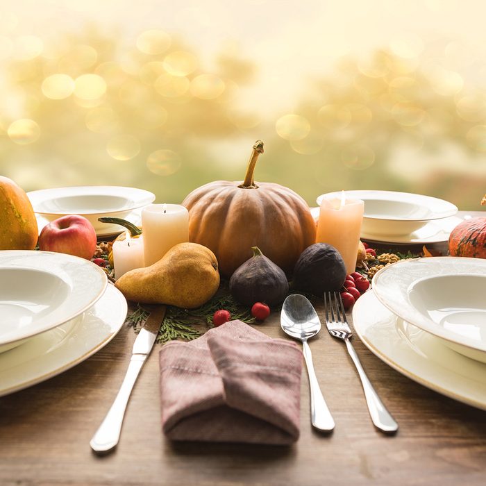 Four plates with cutlery and autumnal vegetables on wooden table