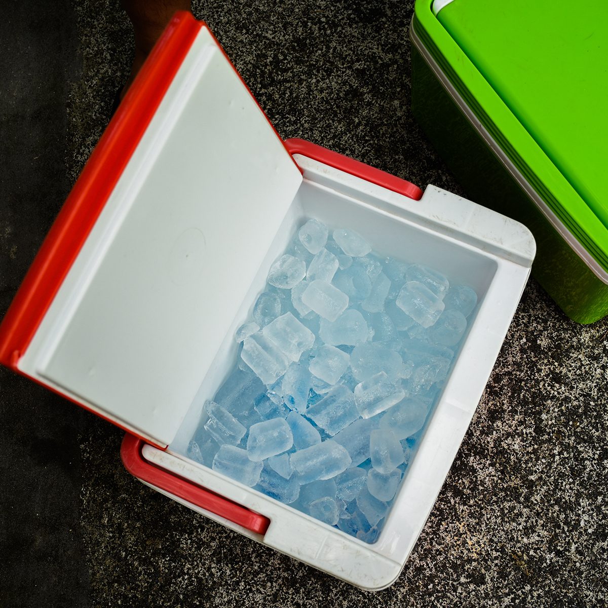 Top view of picnic cooler box with and ice cube on the ground for camping during summer vacation time.
