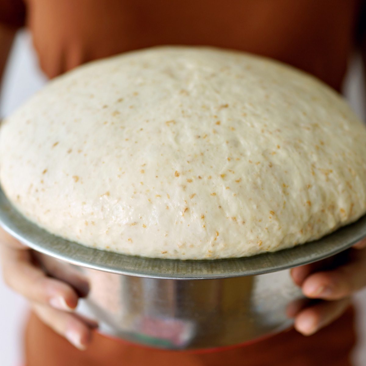 Female holding bowl of bread dough after 2 hours of proofing