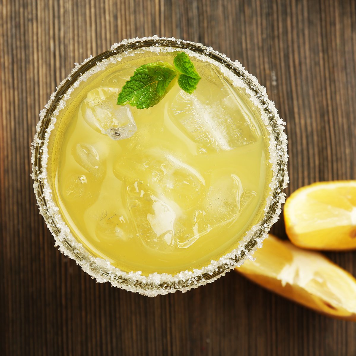 Glass of lemon juice on wooden table, top view