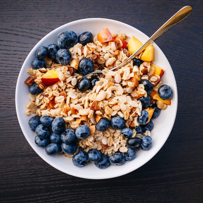 Healthy eating - bowl of organic porridge with blueberry and peach fruits for breakfast.