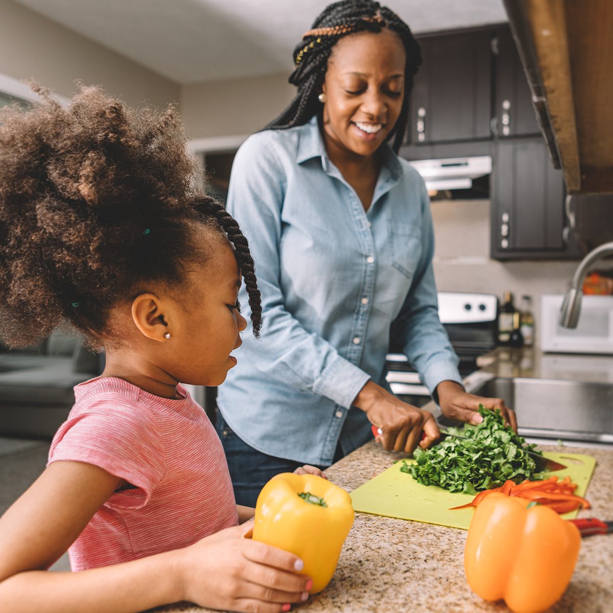 Daughter looking at mother cut vegetables.