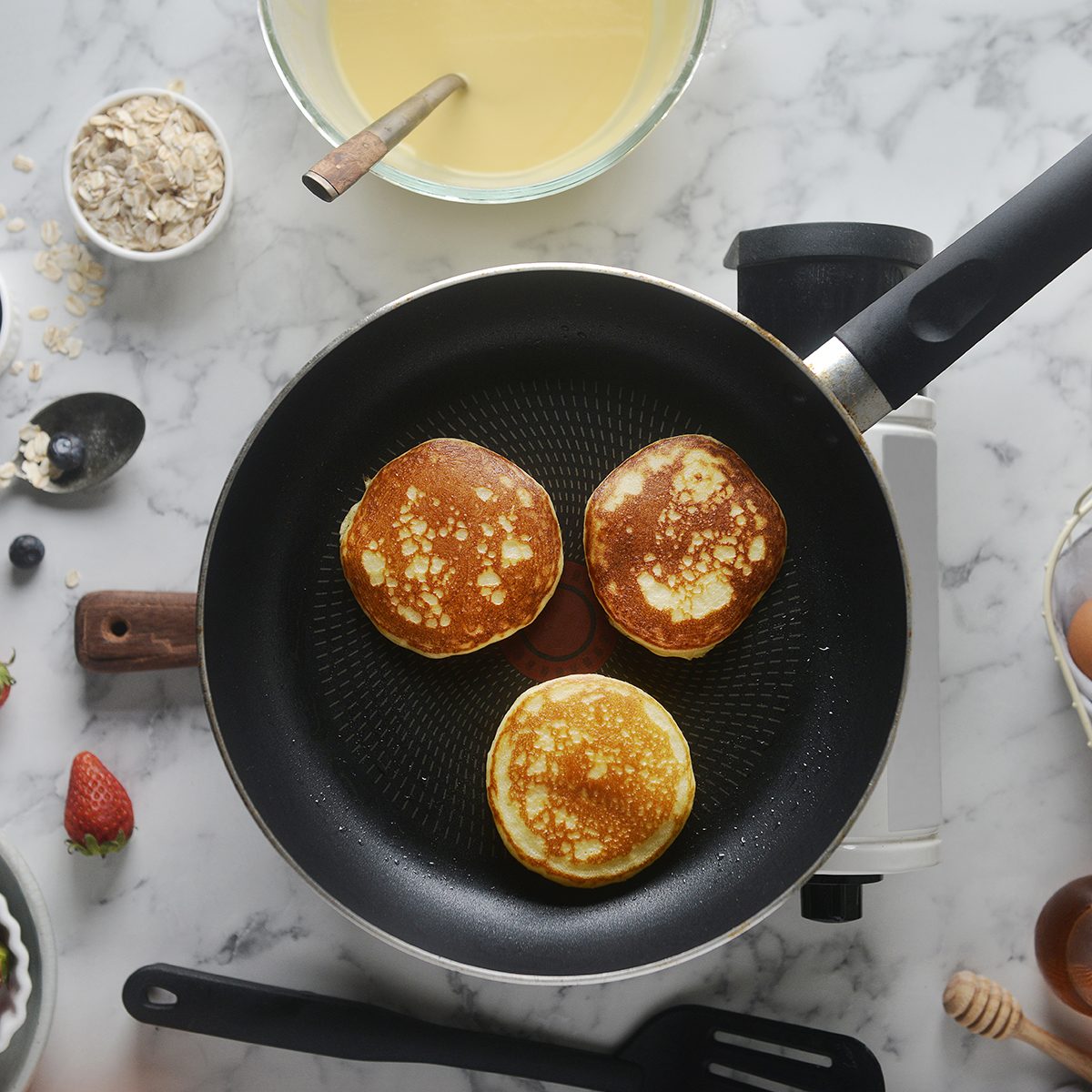 Pancakes onto the pan. Concept of Cooking ingredients and method on white marble background, Dessert recipes and homemade.