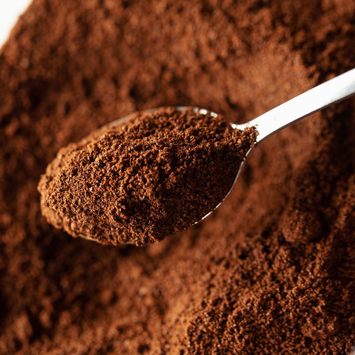 Ground coffee in spoon, natural coffee background, macro