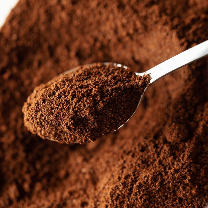 Ground coffee in spoon, natural coffee background, macro