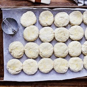 Raw buttermilk southern biscuit or scone dough from scratch with egg brush washed on arranged with rolling pin, biscuit cutter and basting brush. Top view.