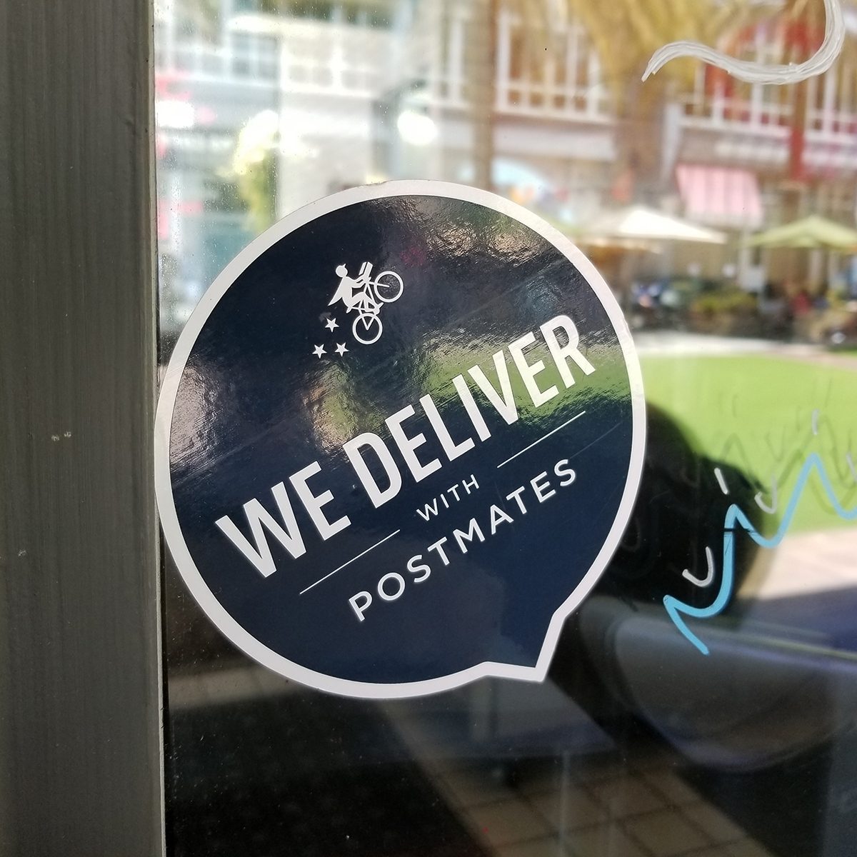 Close-up of logo reading We Deliver With Postmates, referencing the Postmates food delivery app service, on a restaurant window in the Silicon Valley, San Jose, California, June 7, 2018. (Photo by Smith Collection/Gado/Getty Images)
