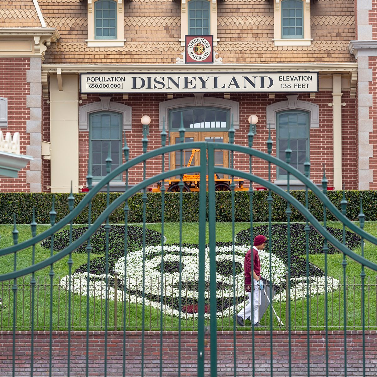 An employee cleans the grounds behind the closed gates of Disneyland Park on the first day of the closure of Disneyland and Disney California Adventure theme parks as fear of the spread of coronavirus continue, in Anaheim, California, on March 14, 2020. - The World Health Organization said March 13, 2020 it was not yet possible to say when the COVID-19 pandemic, which has killed more than 5,000 people worldwide, will peak. "It