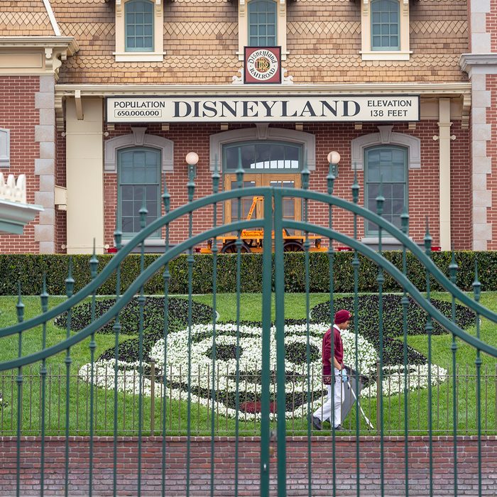 An employee cleans the grounds behind the closed gates of Disneyland Park on the first day of the closure of Disneyland and Disney California Adventure theme parks as fear of the spread of coronavirus continue, in Anaheim, California, on March 14, 2020. - The World Health Organization said March 13, 2020 it was not yet possible to say when the COVID-19 pandemic, which has killed more than 5,000 people worldwide, will peak. "It