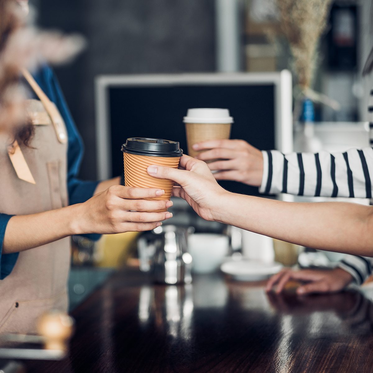 Barista served take away hot coffee cup to customer at counter bar in cafe restaurant,coffee shop business owner concept,Service mind waitress