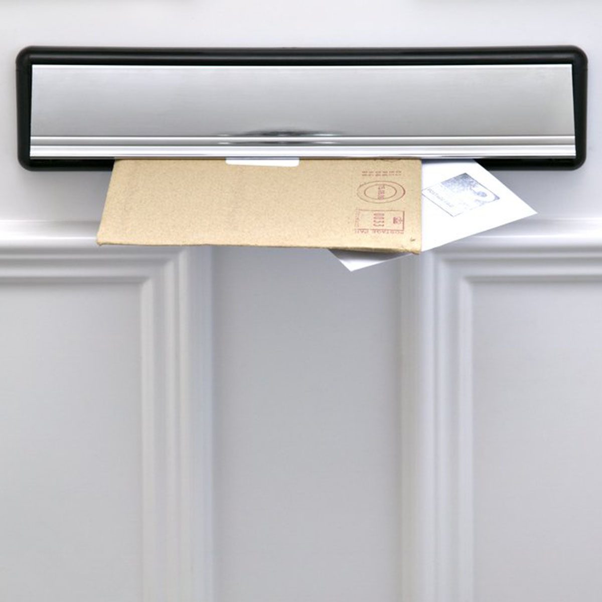 Two letters sticking out of a letterbox on a white door, space for copy