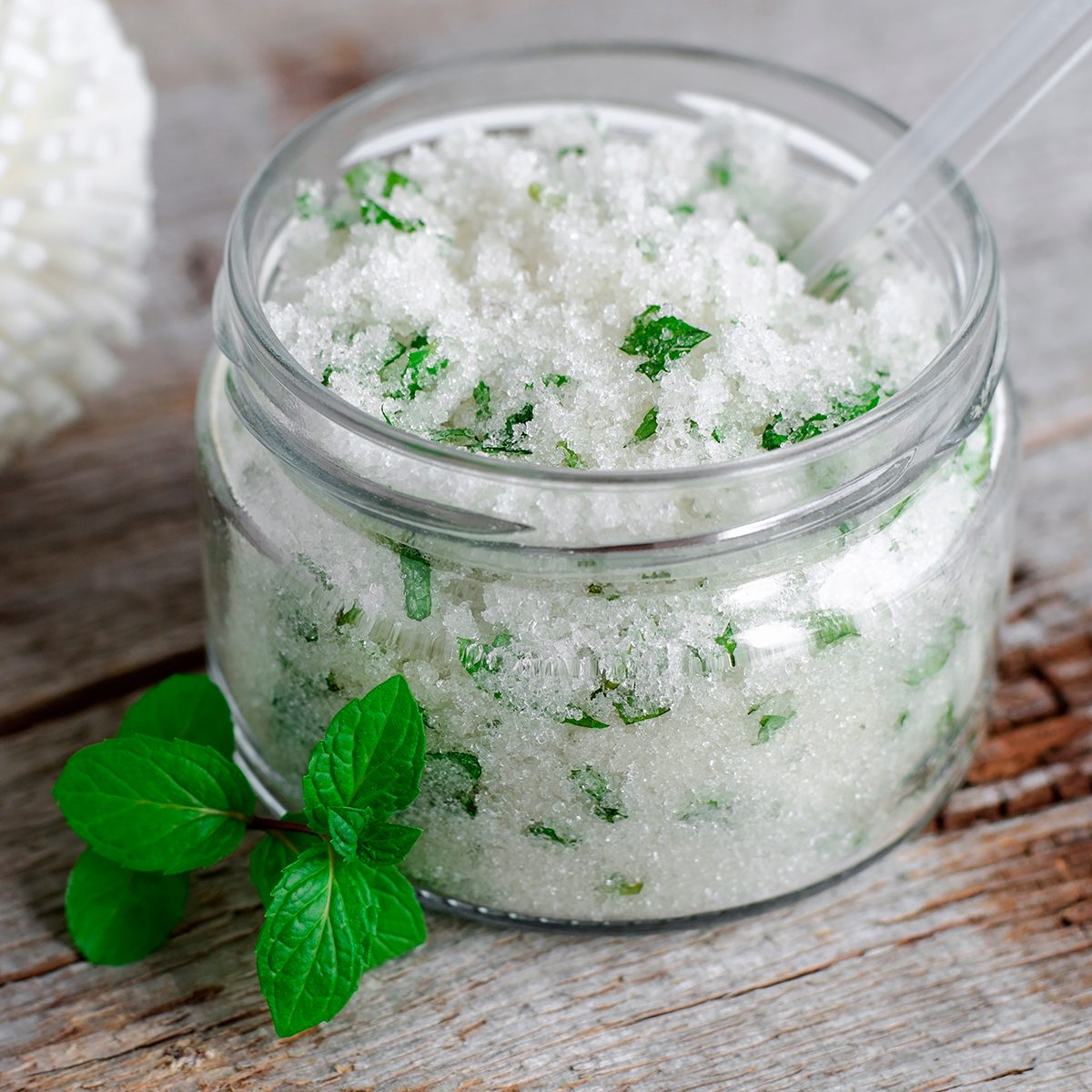Refreshing homemade sugar scrub with vegetable oil, chopped mint leaves and essential mint oil