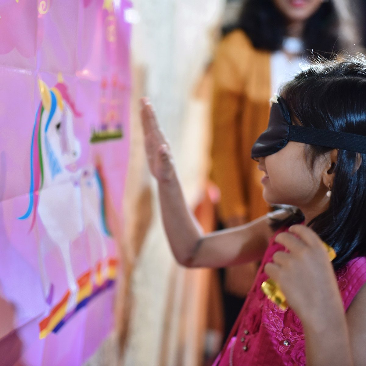 blindfolded girl pinning horn to Unicorn