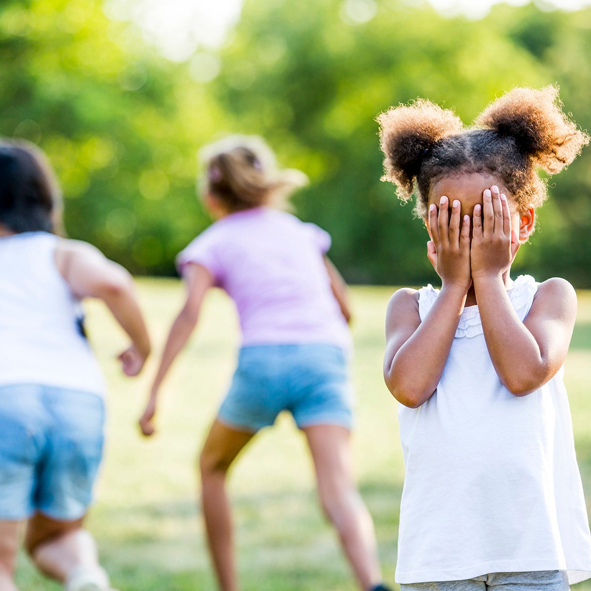 Girls playing hide and seek game in park.