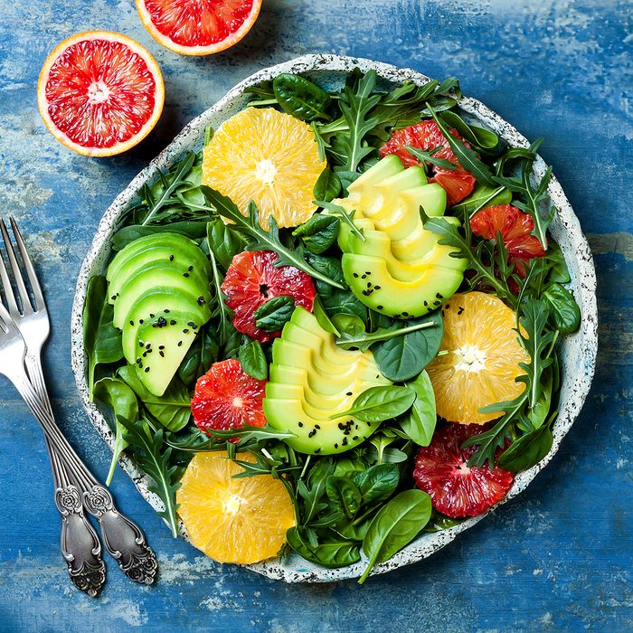 Citrus salad with mixed greens and blood orange. Vegan, vegetarian, clean eating, dieting, food concept. Blue stone background.
