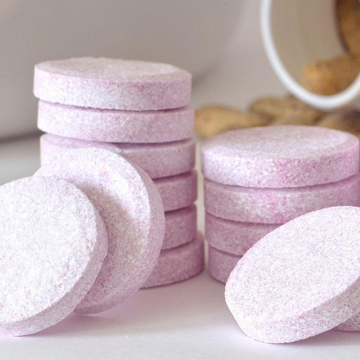 Macro detail of soluble magnesium tablets and bottle of multivitamin supplement pills in foreground