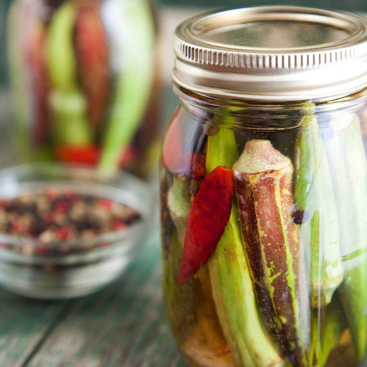 Two jars of pickled okra rest on a primitive country chair.