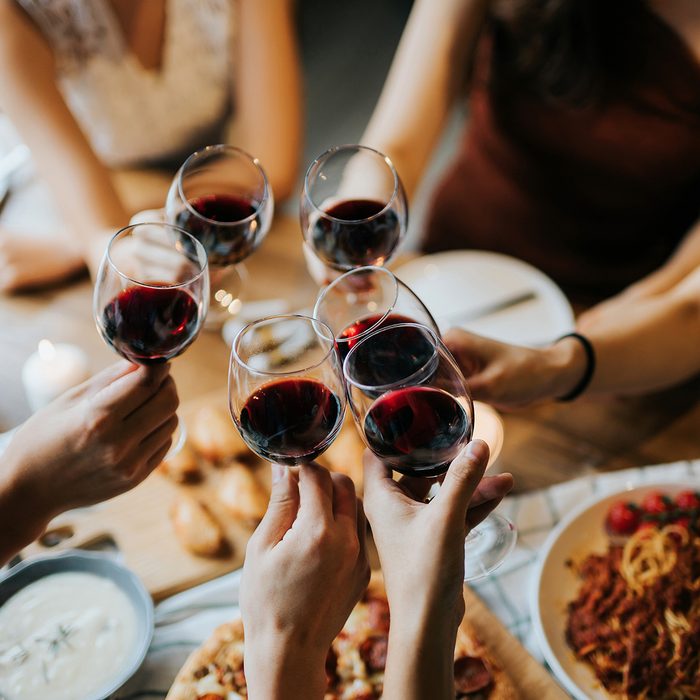Close up of happy young friends having fun and toasting and celebrating with red wine during party