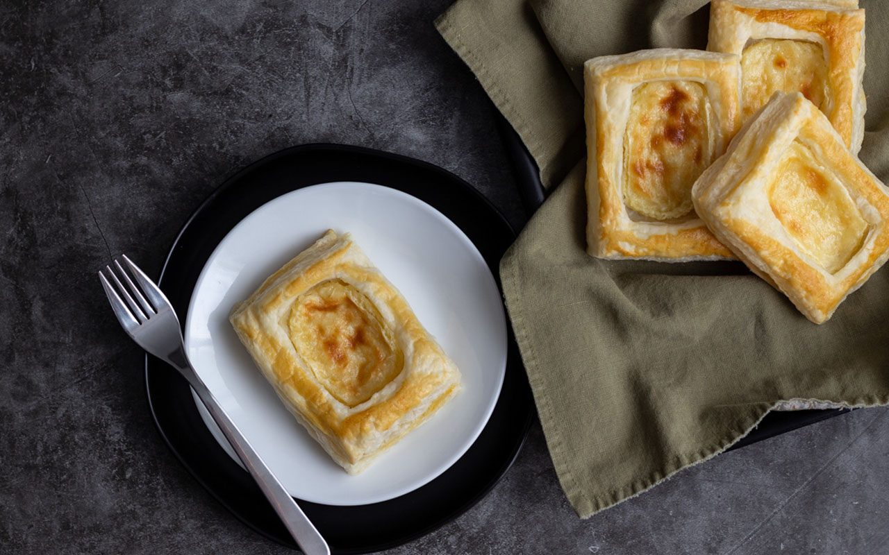 Danish on a plate next to tray of more Danish. starbucks cheese danish copycat