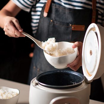 Woman Taking Out And Serving Fresh Boiled Rice From The Cooker