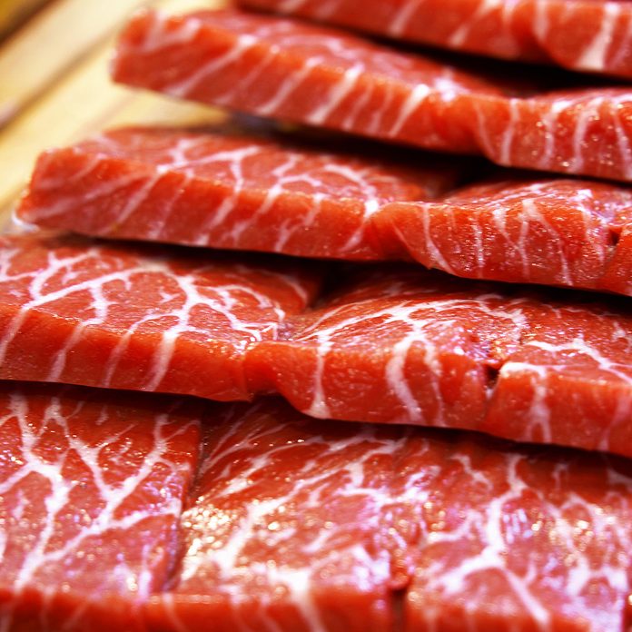 Premium Rare Slices Wagyu A5 beef with high-marbled texture on square wooden plate served for Sukiyaki and Shabu.