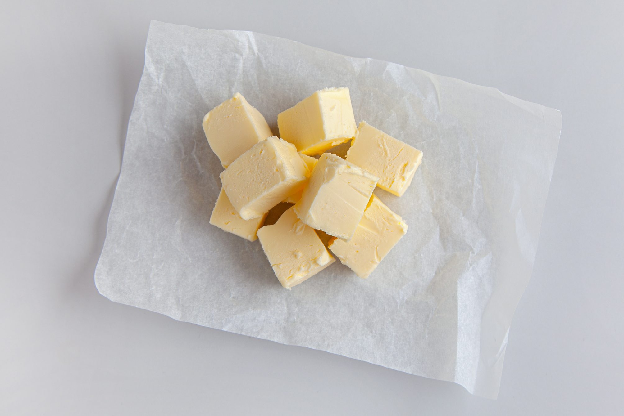 pieces of butter on wrapping paper on grey kitchen table background