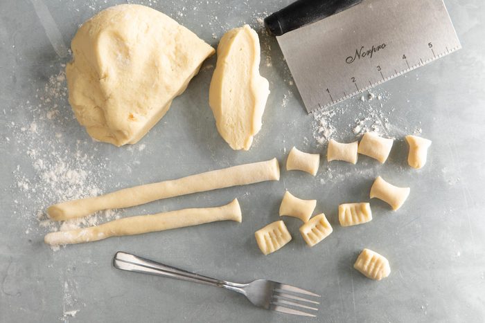 kneaded Gnocchi dough cut into sections and some sections have been rolled with some gnocchi being cut
