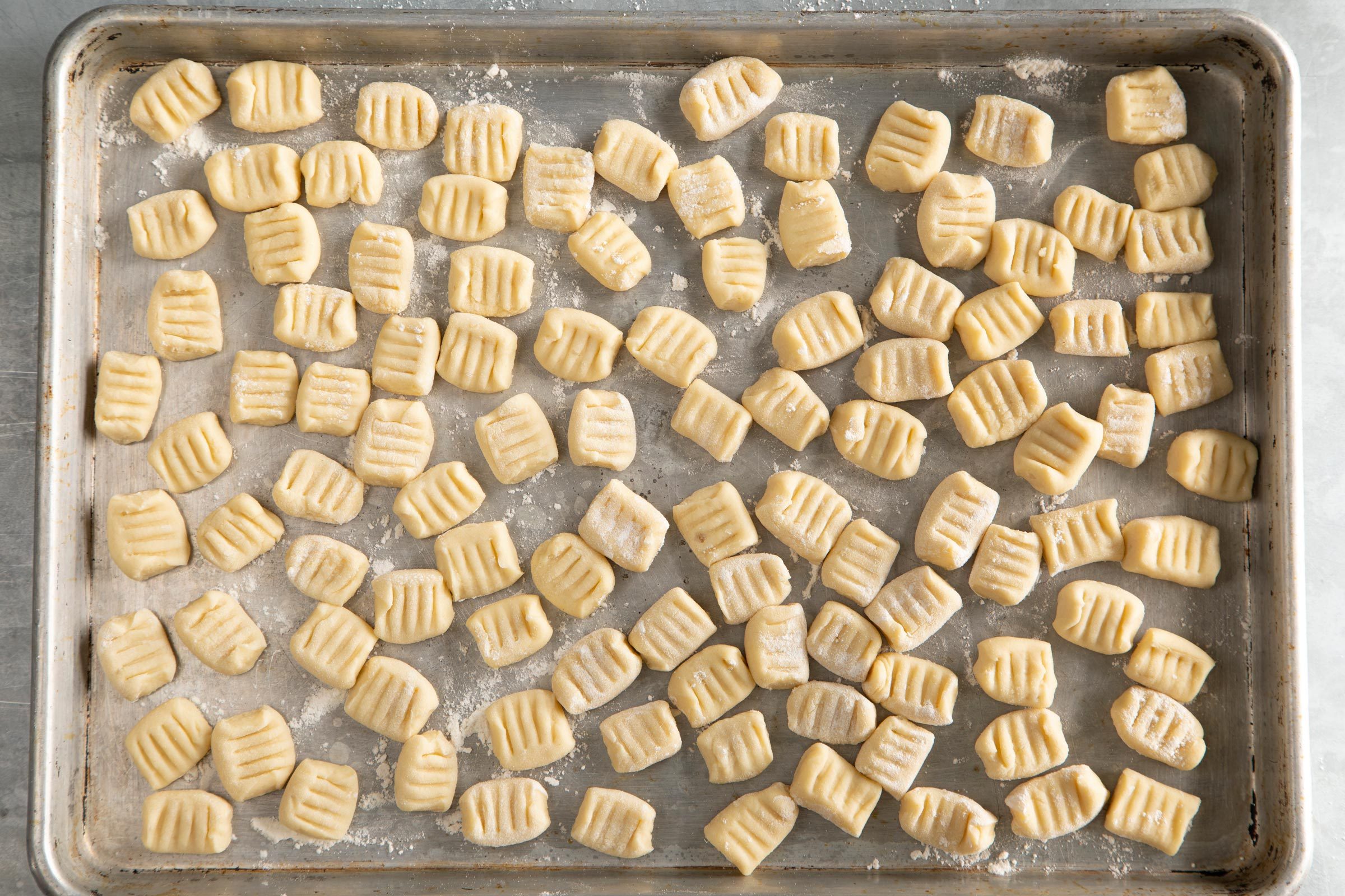 Homemade Gnocchi dumplings spread out on a baking sheet ready to be cooked