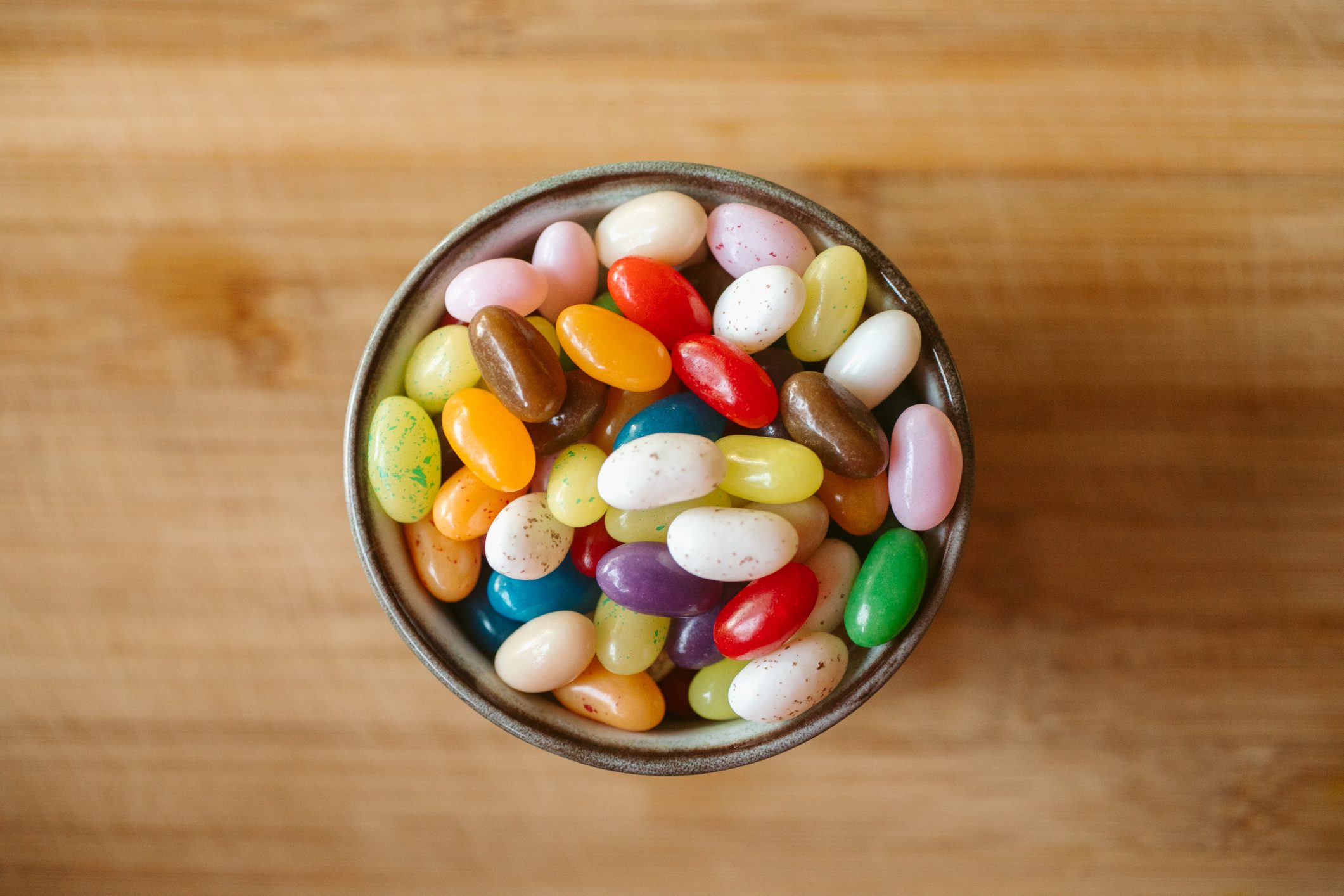 mix of flavors of jellybeans in a bowl on wood background