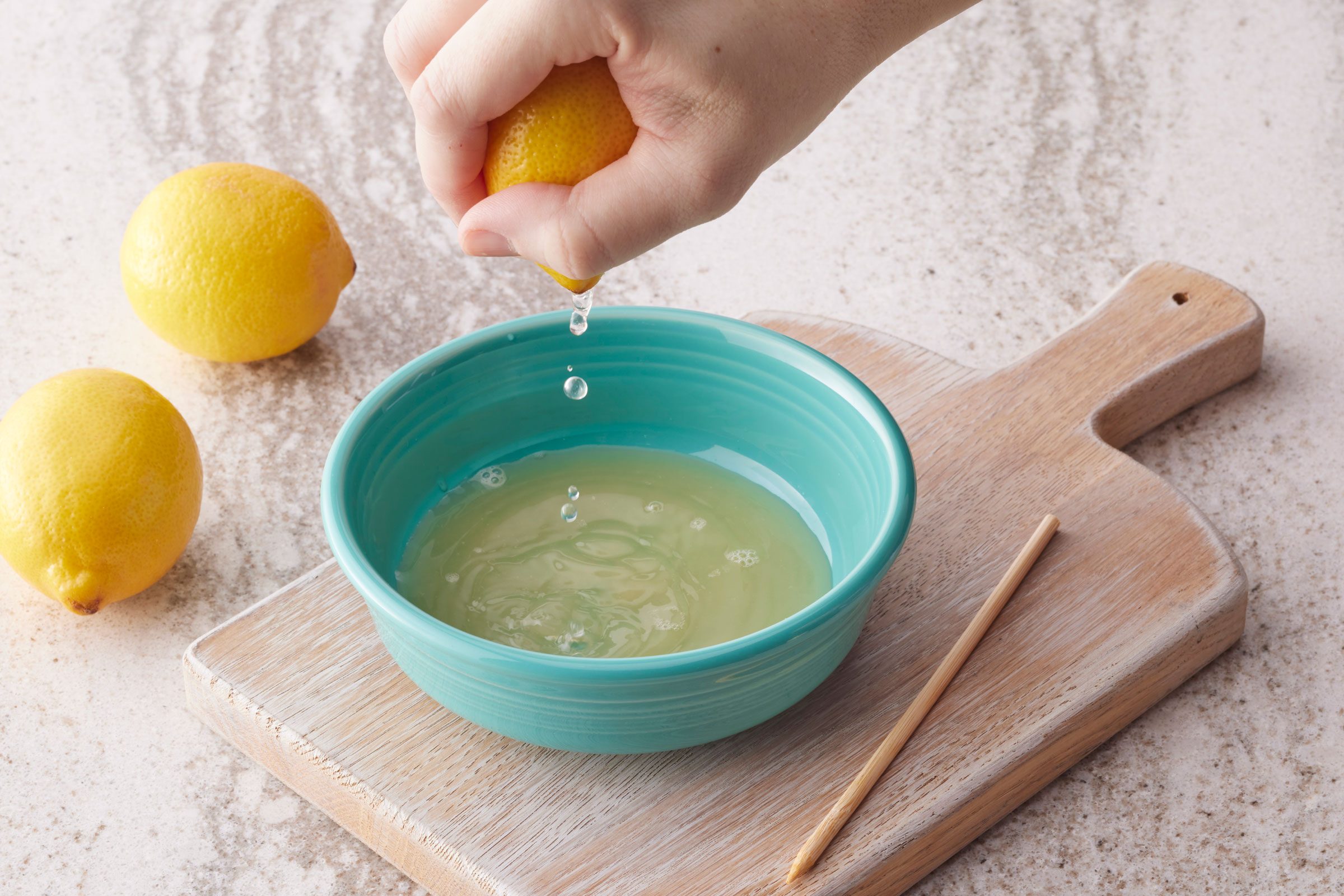 squeezing a lemon into a teal bowl