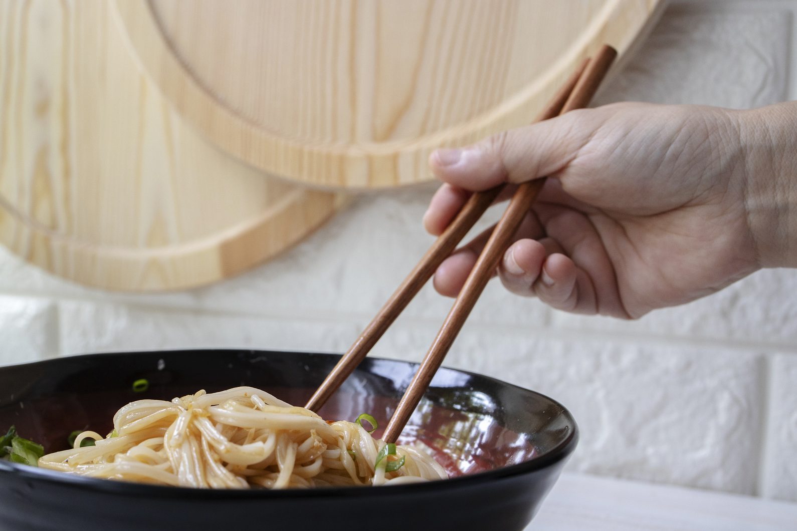 hand holding chopsticks eating Chinese homemade noodles