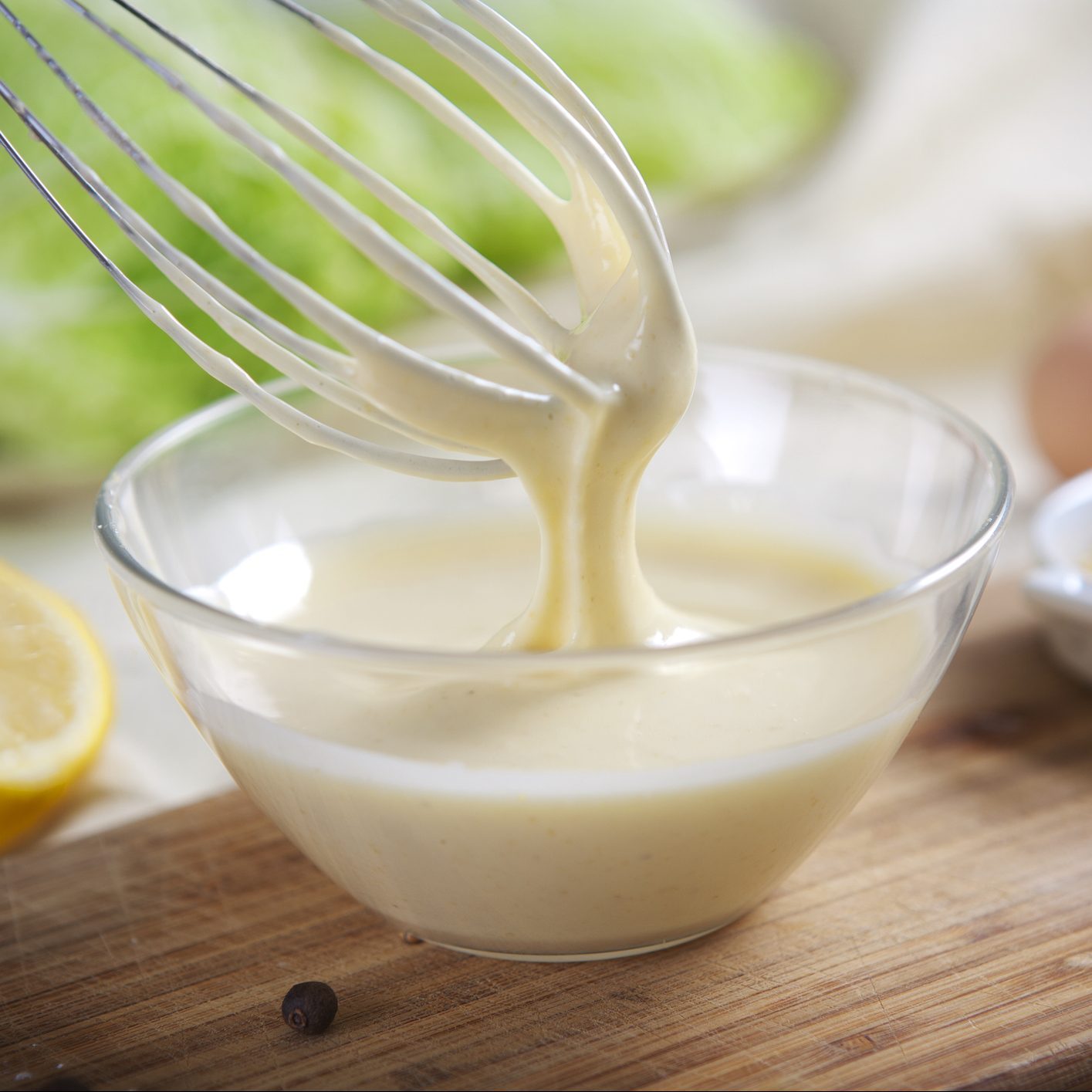 Homemade mayonnaise being whipped in a glass bowl