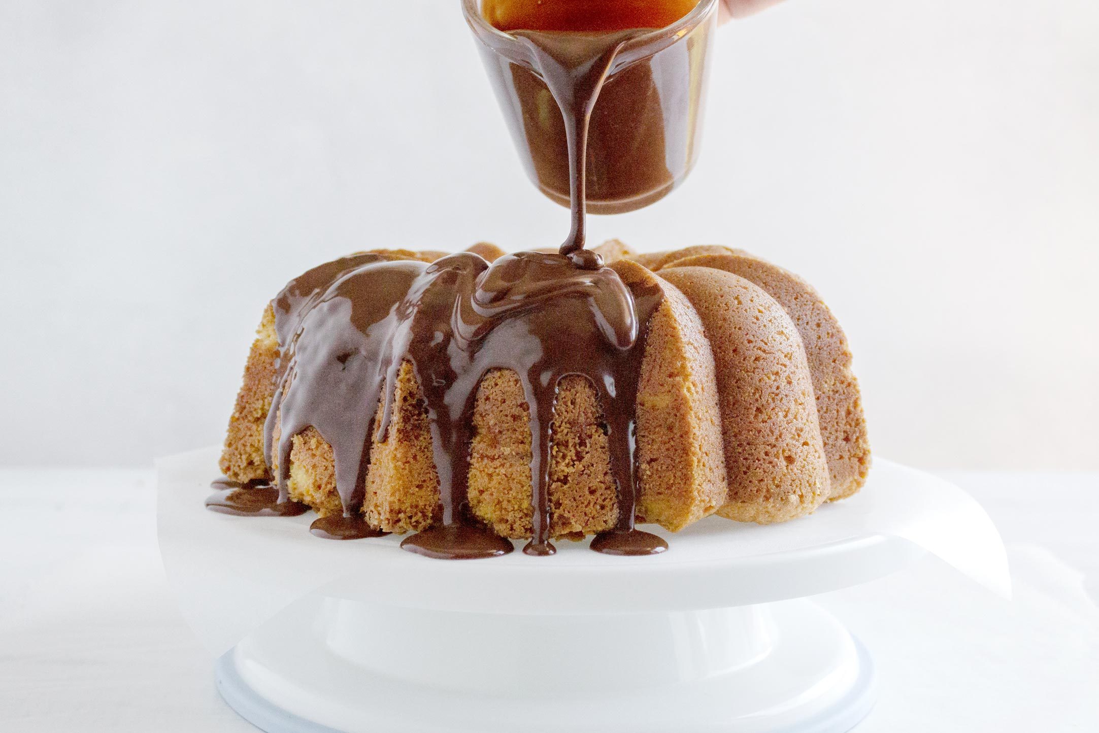 frosting a bundt cake with chocolate ganache