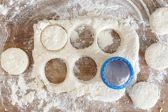 using a cookie cuttter to cut out circles from a sheet of Cottage Cheese Biscuit dough