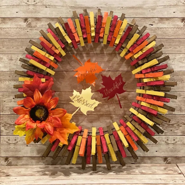 fall clothes pin wreath with faux lflowers and leaves as an accent