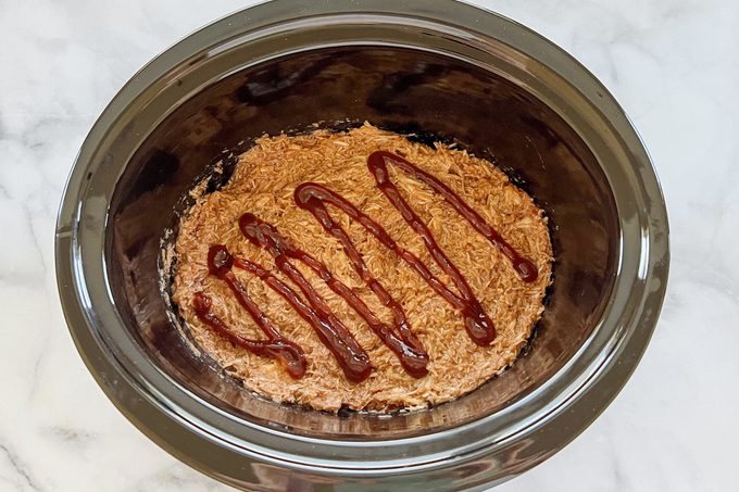 cooked shredded chicken in a crock pot with bbq sauce