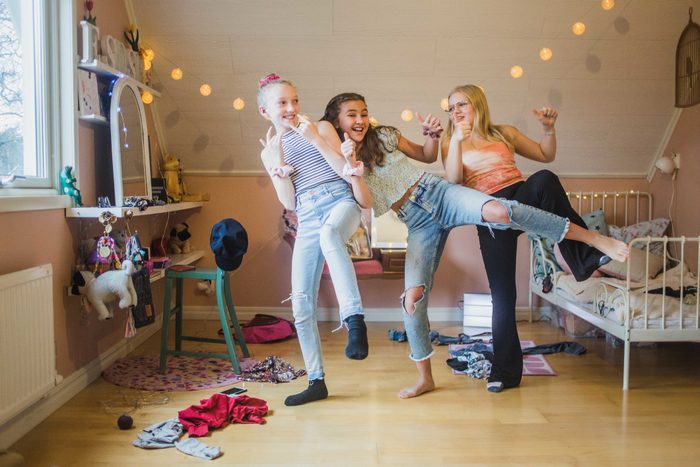Cheerful female friends enjoying dancing together in bedroom